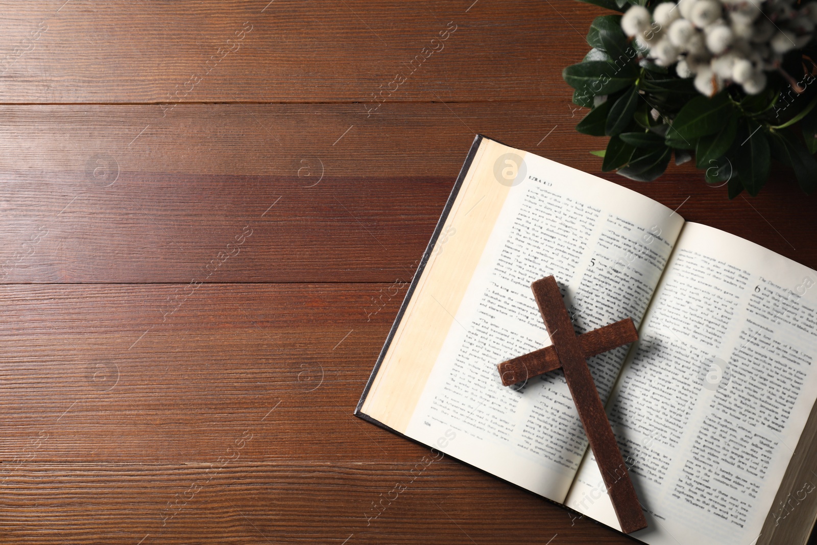 Photo of Bible, plant with willow branches and cross on wooden table, flat lay. Space for text