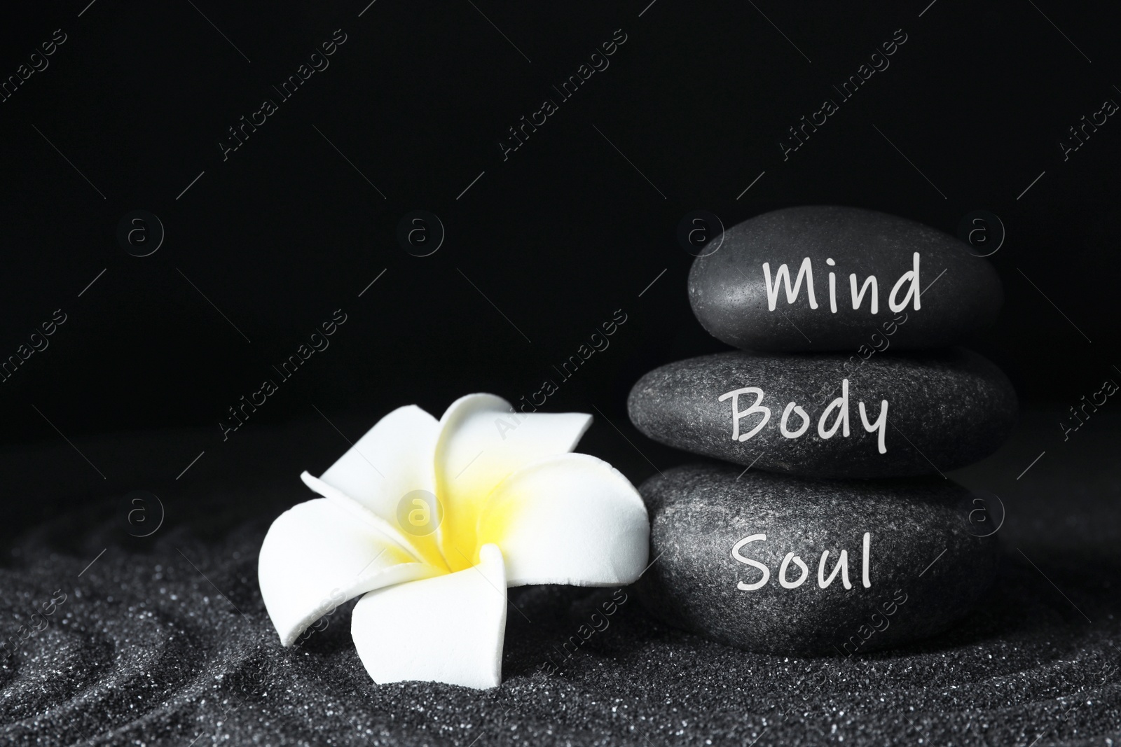 Image of Stones with words Mind, Body, Soul and plumeria flower on sand. Zen lifestyle