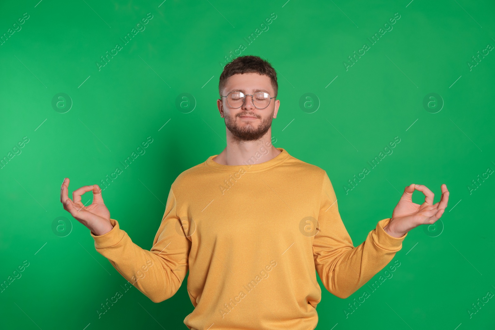 Photo of Young man meditating on green background. Zen concept