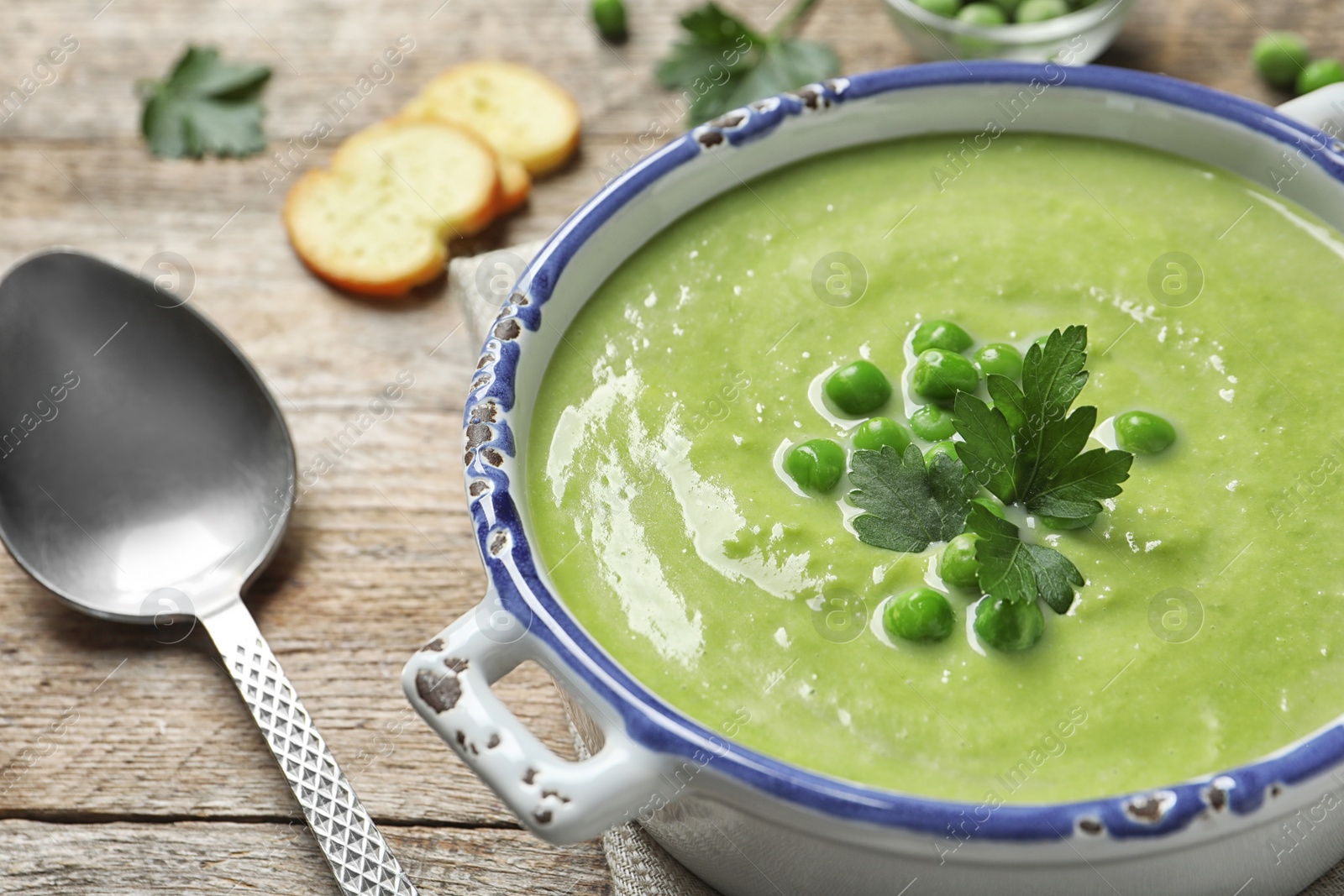 Photo of Fresh vegetable detox soup made of green peas in dish served on table, closeup