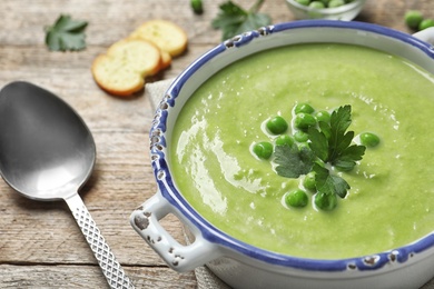 Photo of Fresh vegetable detox soup made of green peas in dish served on table, closeup