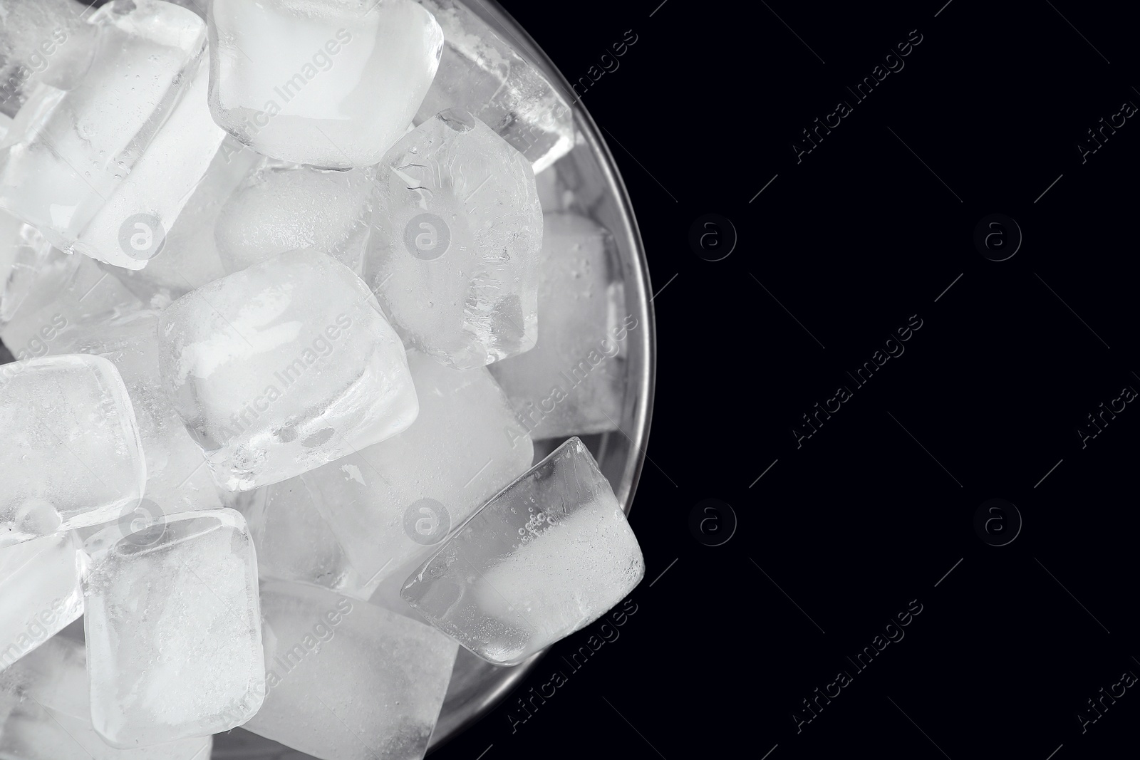 Photo of Metal bucket with ice cubes on black background, top view. Space for text