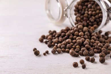 Black pepper grains on white wooden table, closeup