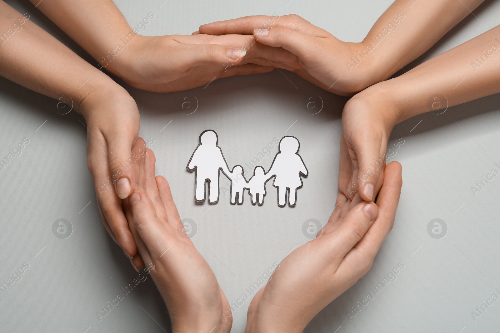 Photo of People with paper family cutout on light grey background, top view