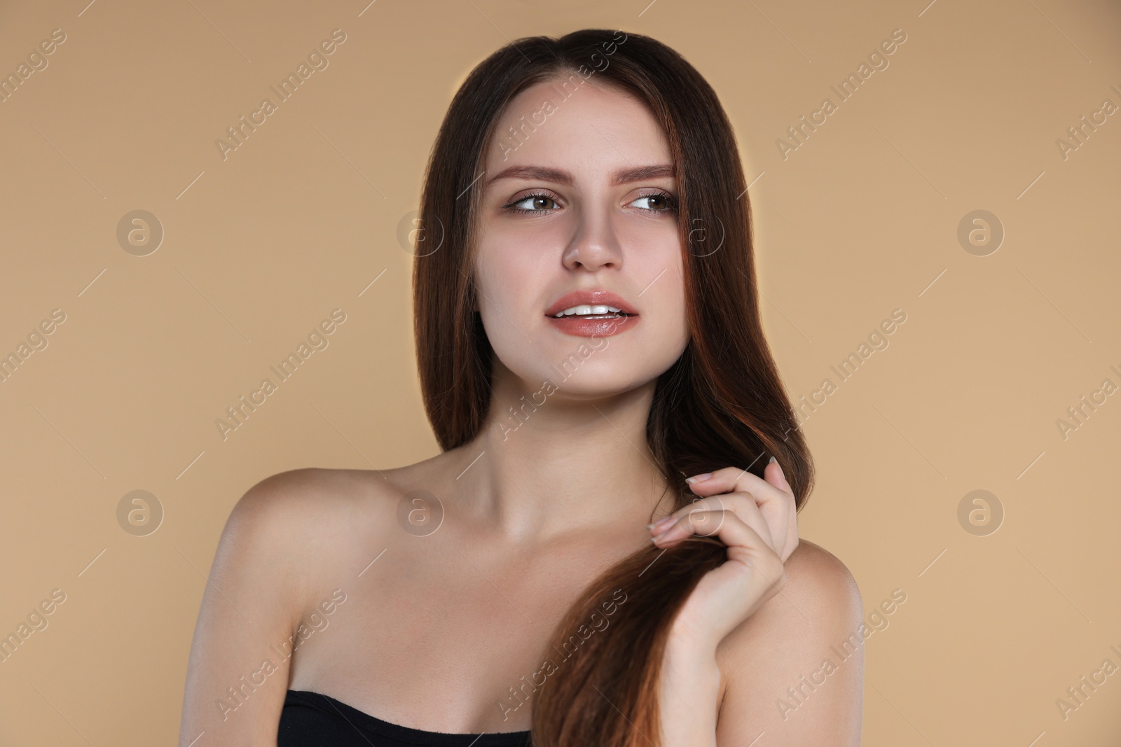 Photo of Young woman with strong healthy hair on beige background