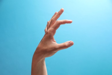 Photo of Man holding something in hand on light blue background, closeup