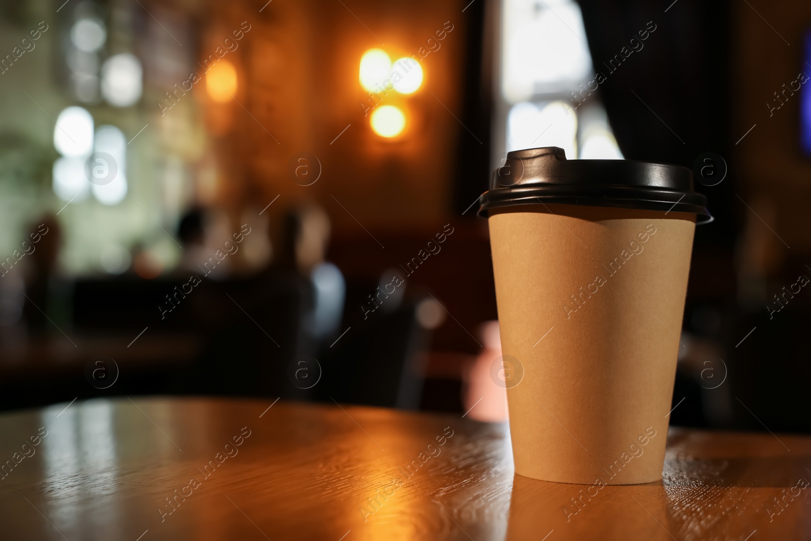 Photo of Paper coffee cup on wooden table in cafe. Space for text