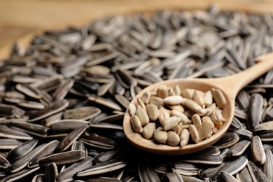 Photo of Wooden spoon and raw sunflower seeds, closeup