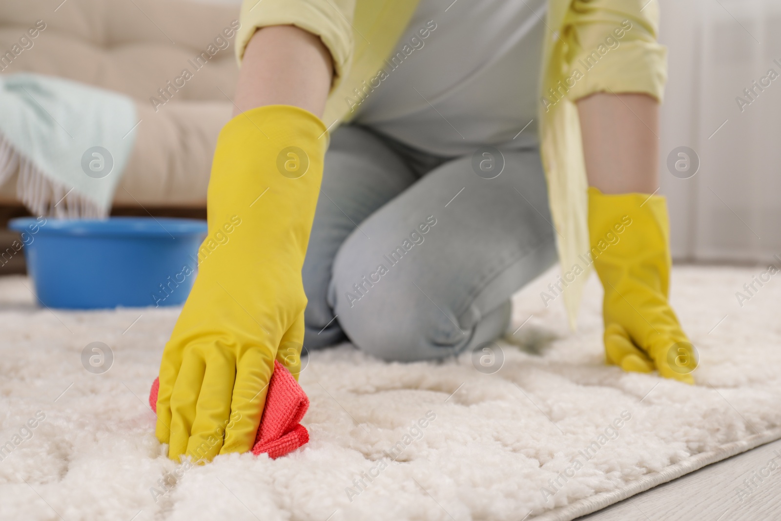 Photo of Woman in rubber gloves cleaning carpet with rag indoors, closeup. Space for text