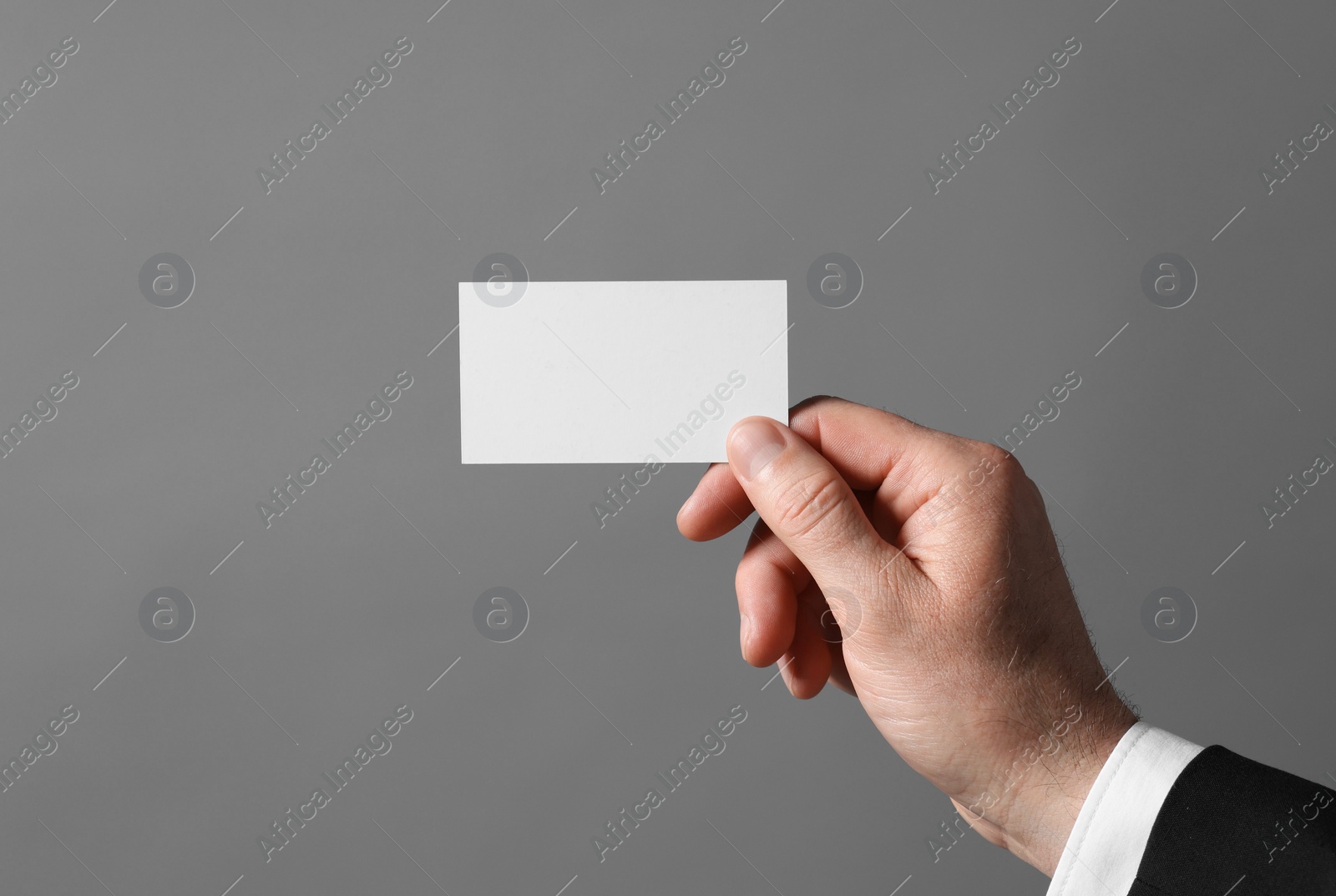 Photo of Man holding blank business card on grey background, closeup. Space for text