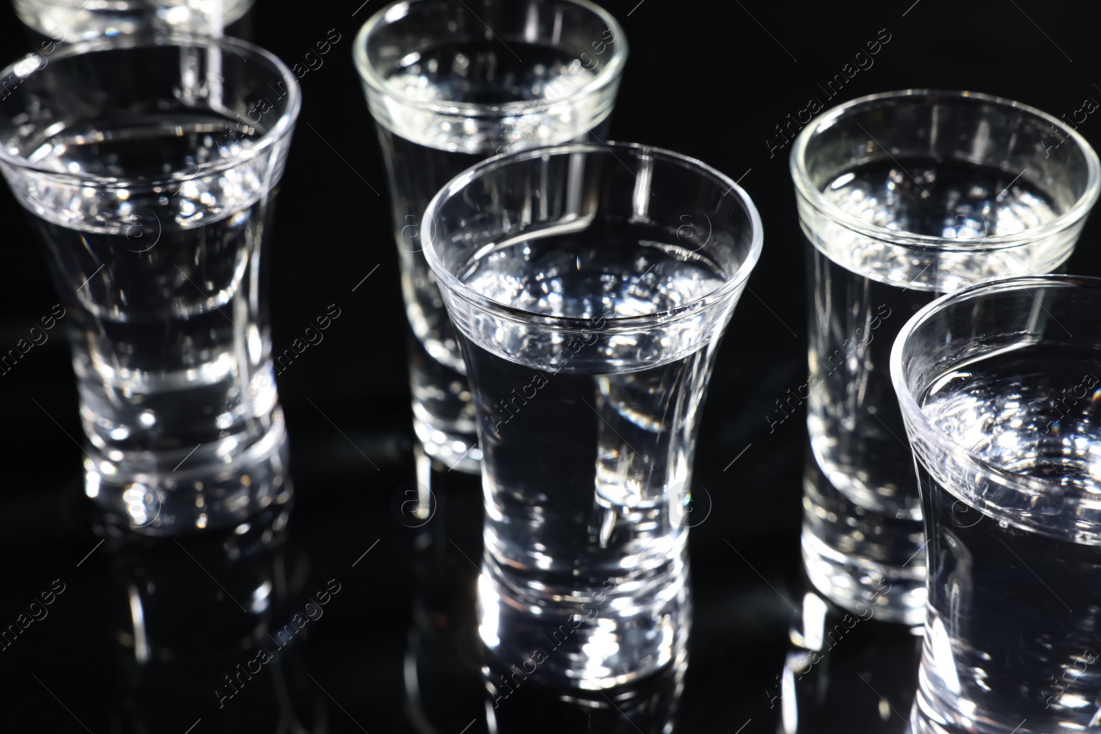 Photo of Shot glasses with vodka on black table