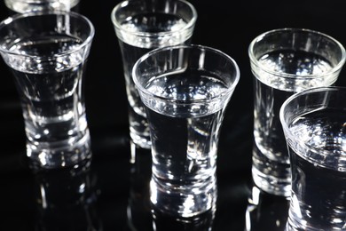 Photo of Shot glasses with vodka on black table