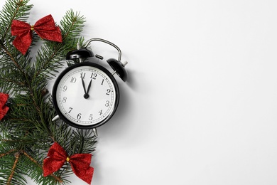 Alarm clock and decorated fir branches on white background, flat lay with space for text. New Year countdown