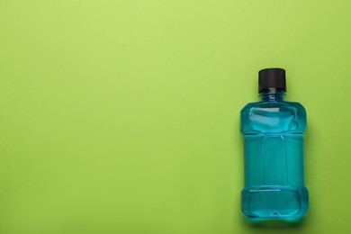 Photo of Mouthwash on light green background, top view. Space for text