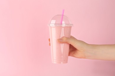 Photo of Woman holding plastic cup of tasty smoothie on pink background, closeup