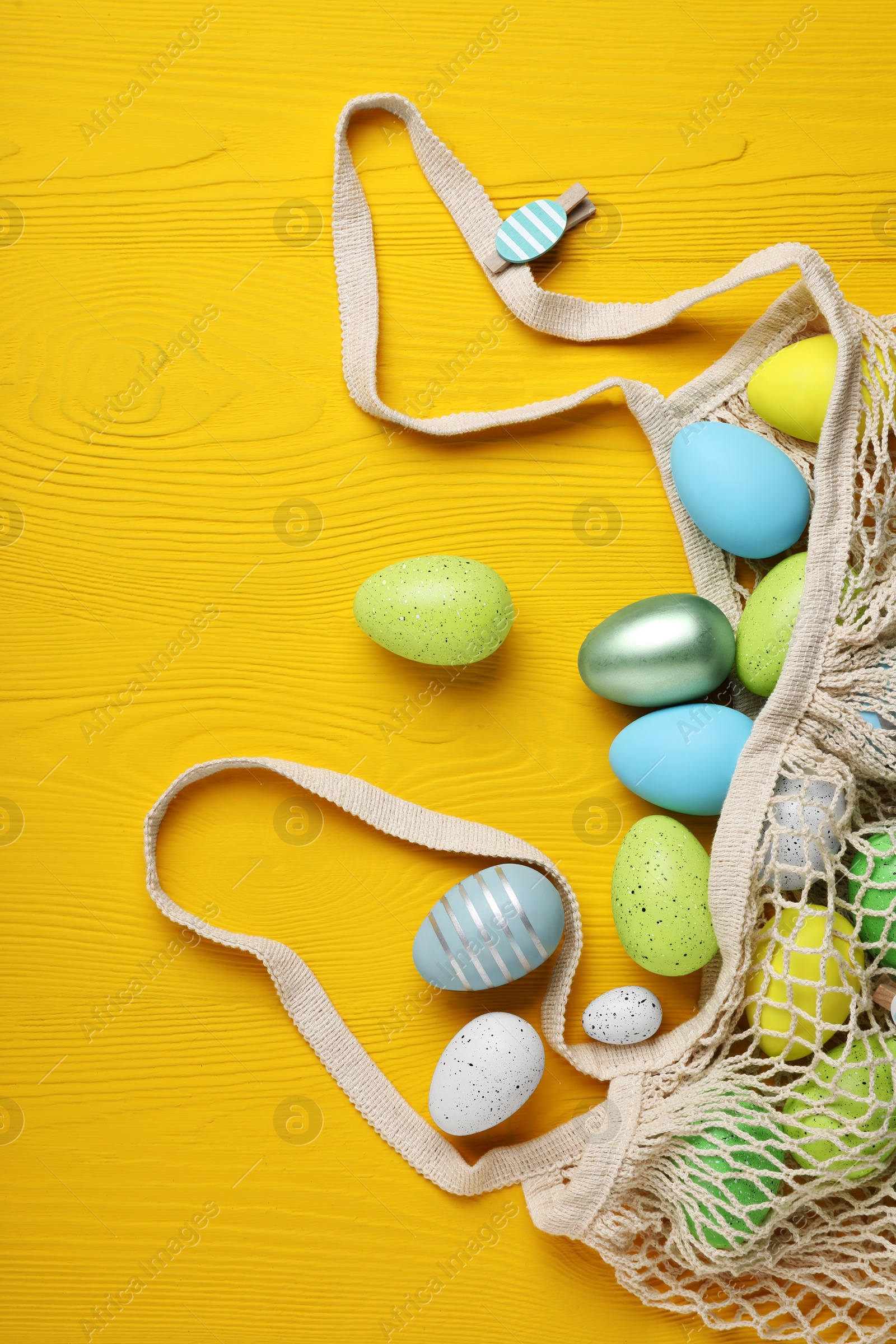 Photo of Many beautifully decorated Easter eggs on yellow wooden table, flat lay