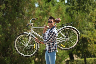 Photo of Handsome young hipster man with bicycle in park