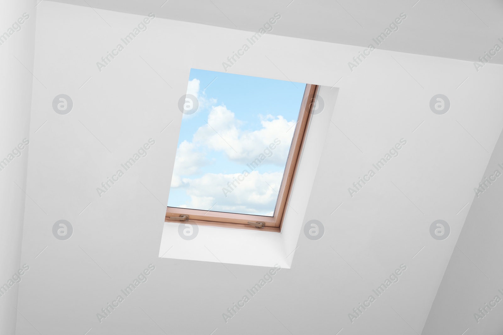 Photo of Skylight roof window and lamps on slanted ceiling in attic room, low angle view