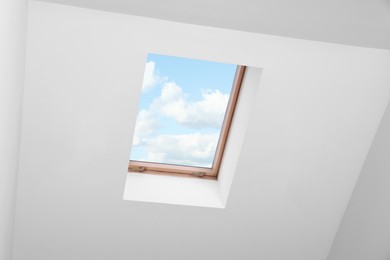 Photo of Skylight roof window and lamps on slanted ceiling in attic room, low angle view