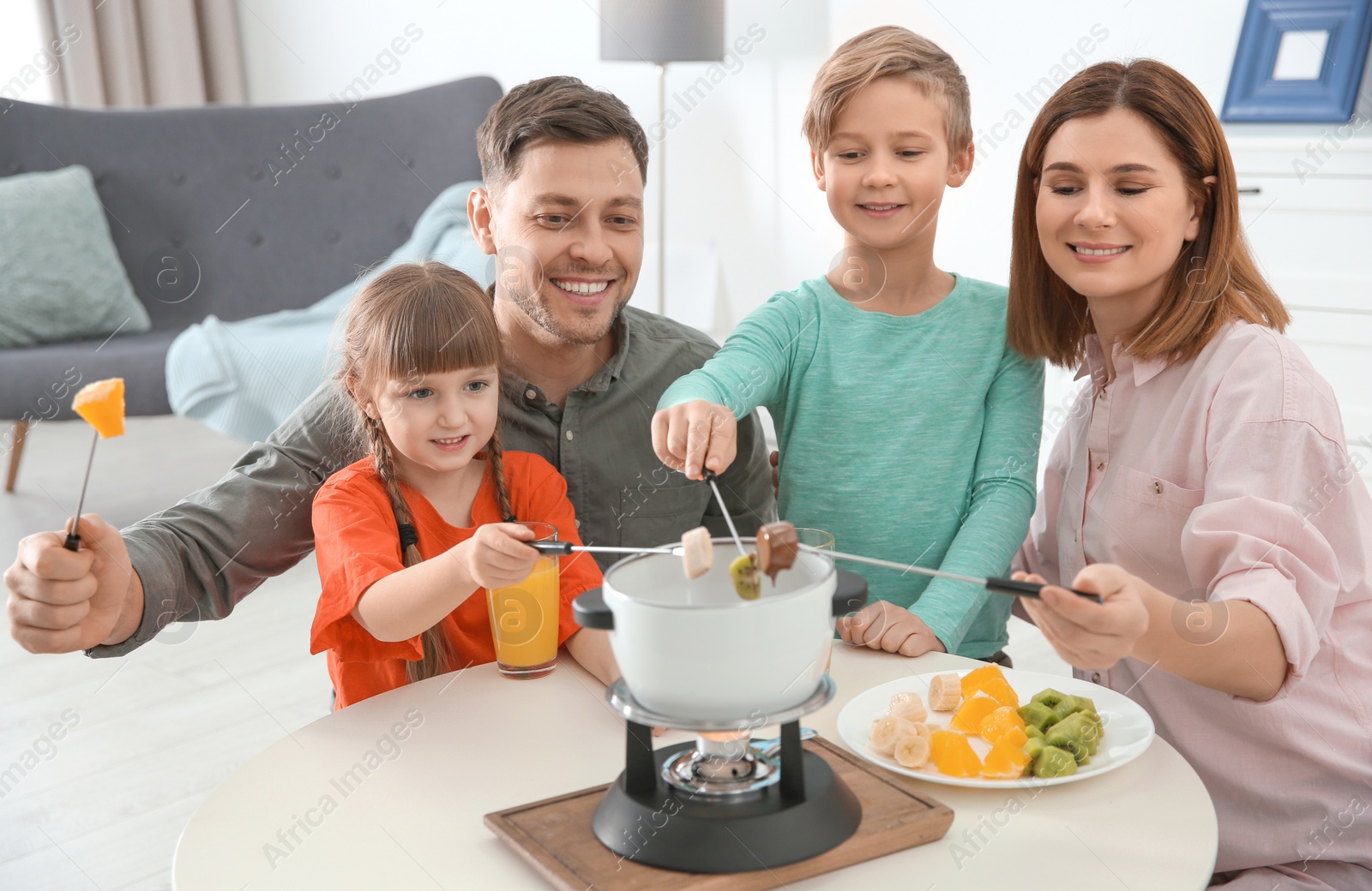 Photo of Happy family enjoying fondue dinner at home