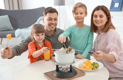 Happy family enjoying fondue dinner at home