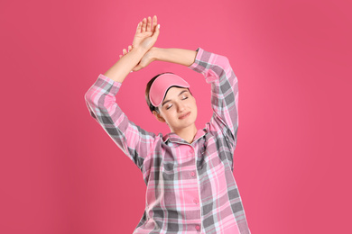 Photo of Beautiful woman wearing sleeping mask on pink background. Bedtime