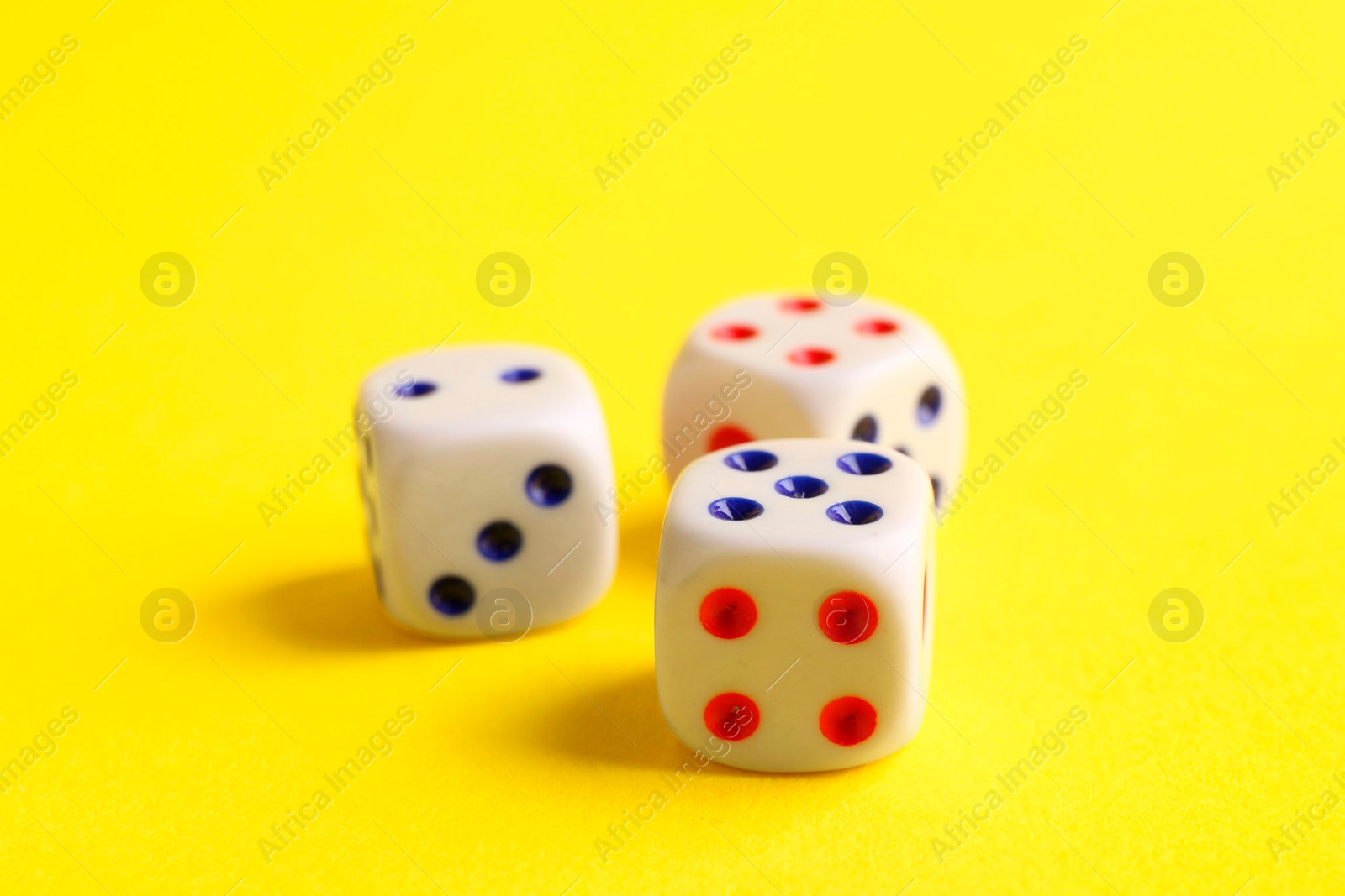 Photo of Three white game dices on yellow background, closeup