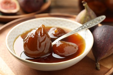 Bowl of tasty sweet fig jam on wooden table, closeup