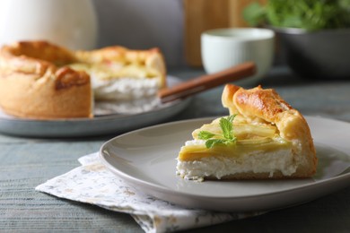 Photo of Piece of freshly baked rhubarb pie with cream cheese and mint leaves on grey wooden table, closeup