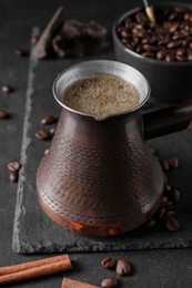 Photo of Cezve with Turkish coffee, beans and cinnamon on grey table