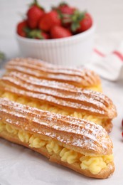 Photo of Delicious eclairs filled with cream on table, closeup