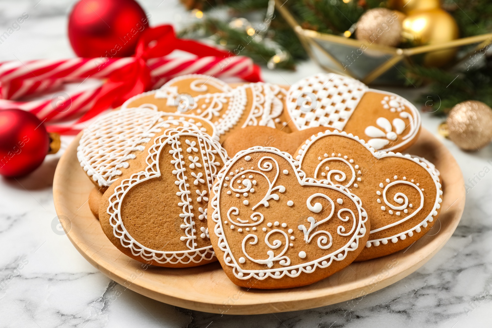 Photo of Tasty heart shaped gingerbread cookies and Christmas decor on white marble table, closeup