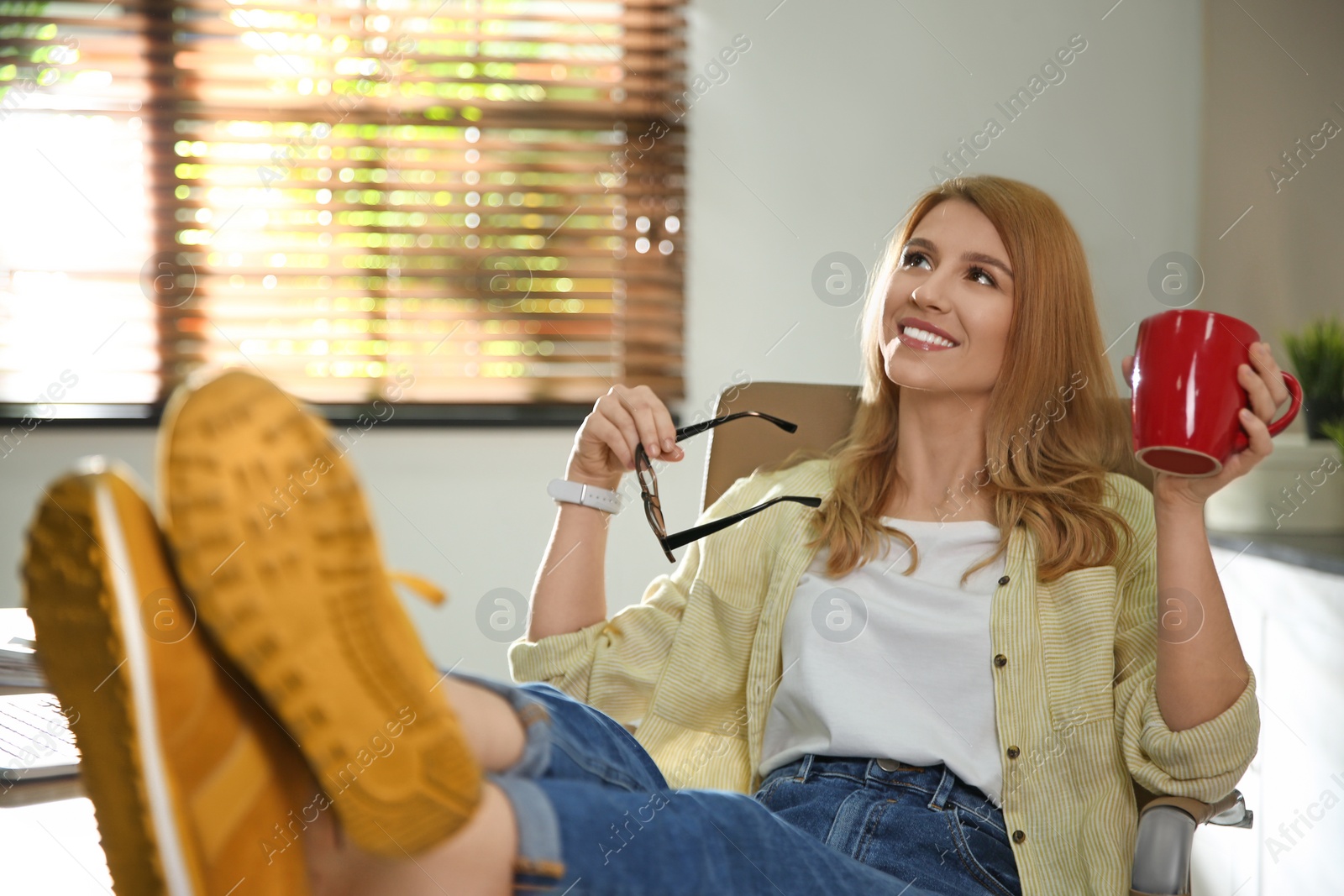 Photo of Young woman with cup of drink relaxing at workplace