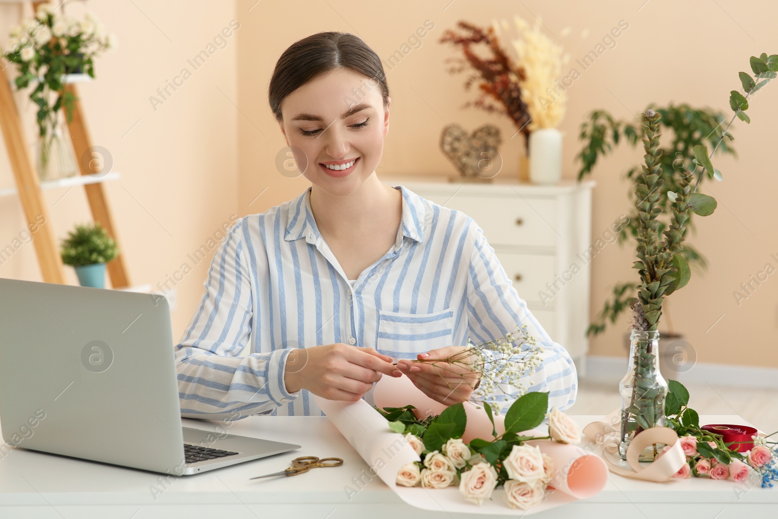 Photo of Woman making bouquet following online florist course at home. Time for hobby