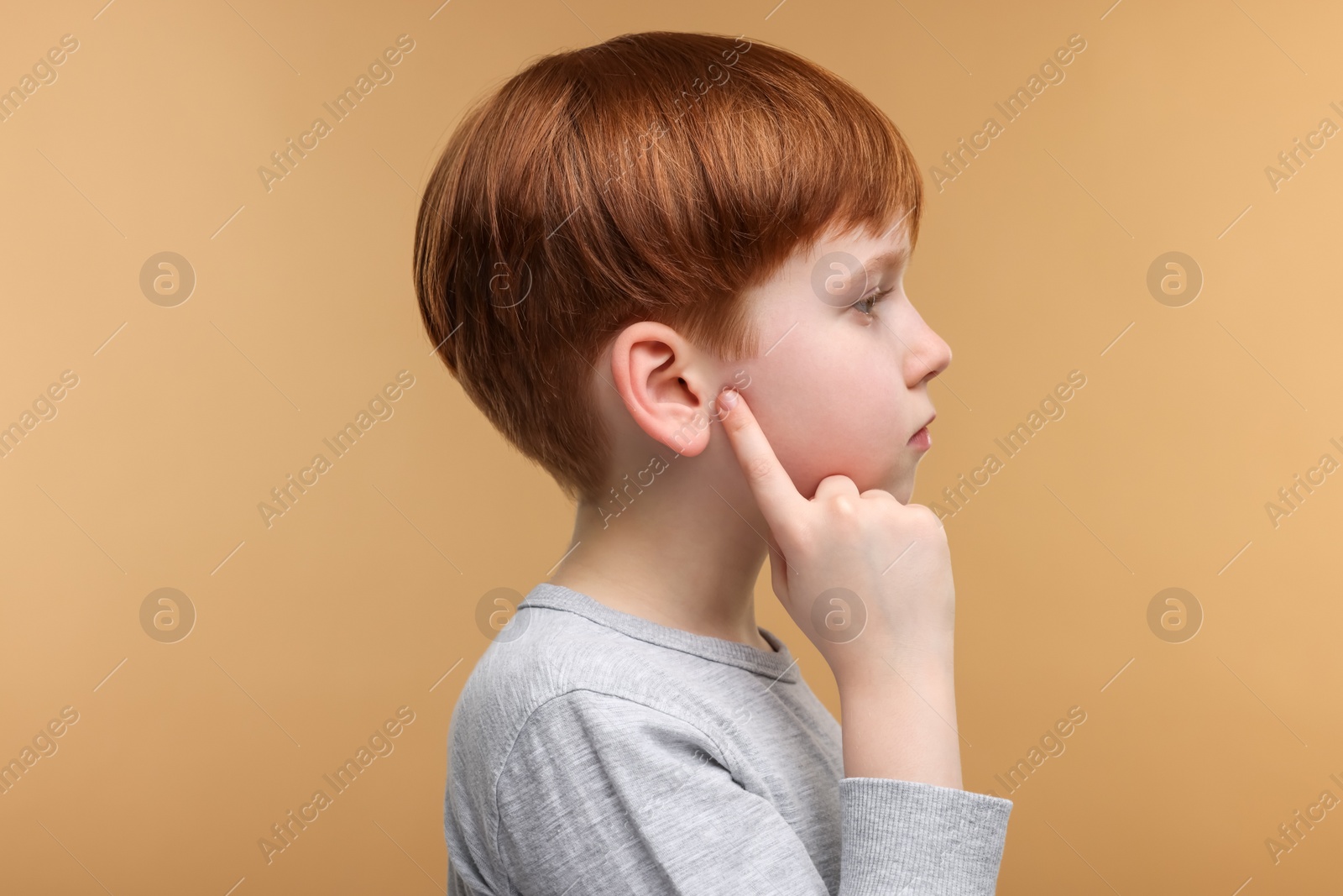 Photo of Little boy with hearing problem on pale brown background