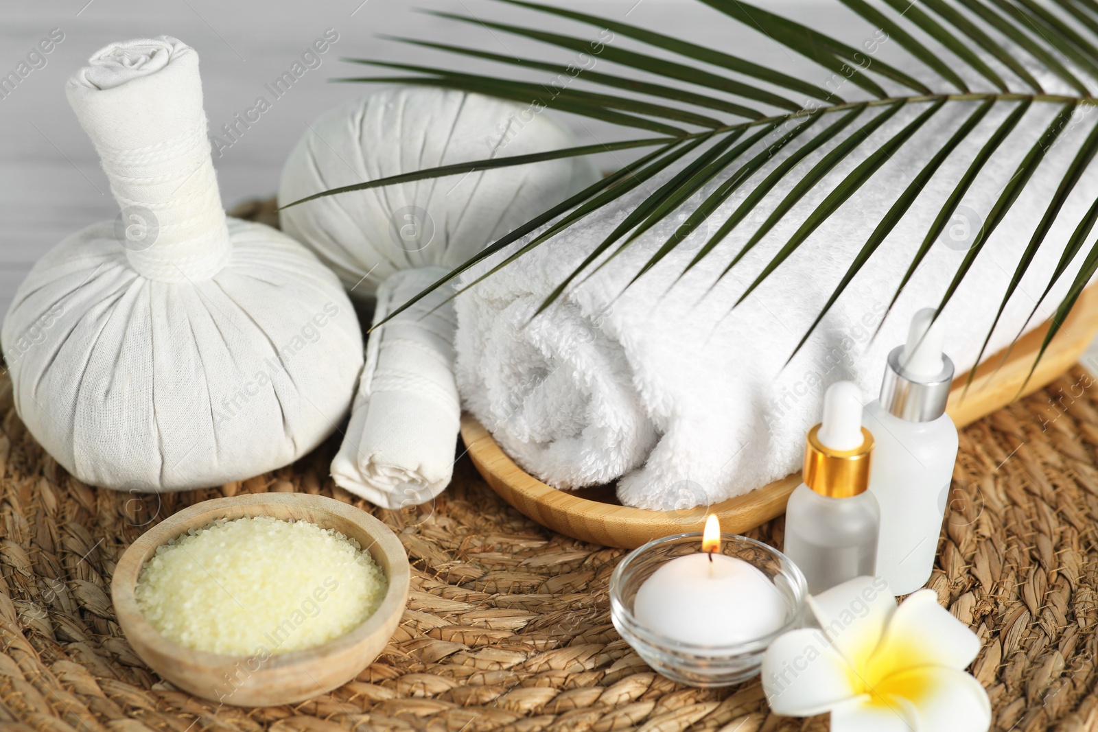 Photo of Composition with different spa products and plumeria flower on wicker mat