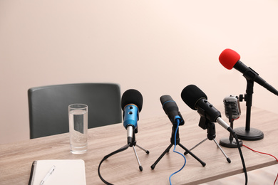 Journalist's microphones on wooden table in room