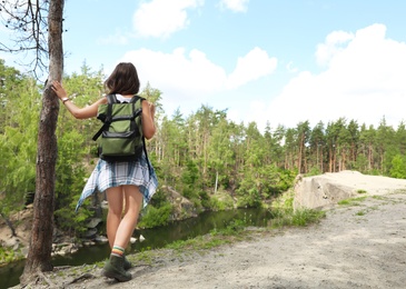 Young woman with backpack in wilderness. Camping season