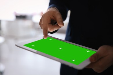 Image of Businessman using digital tablet indoors, closeup. Device display with chroma key