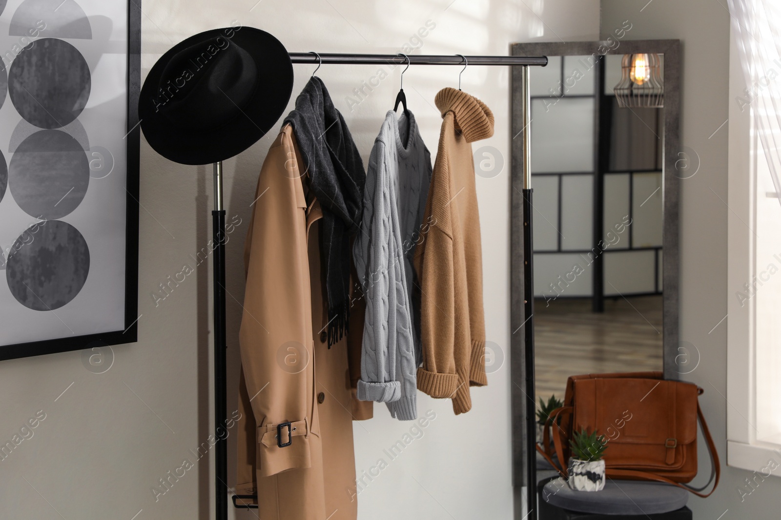 Photo of Stylish warm clothes on rack in dressing room interior