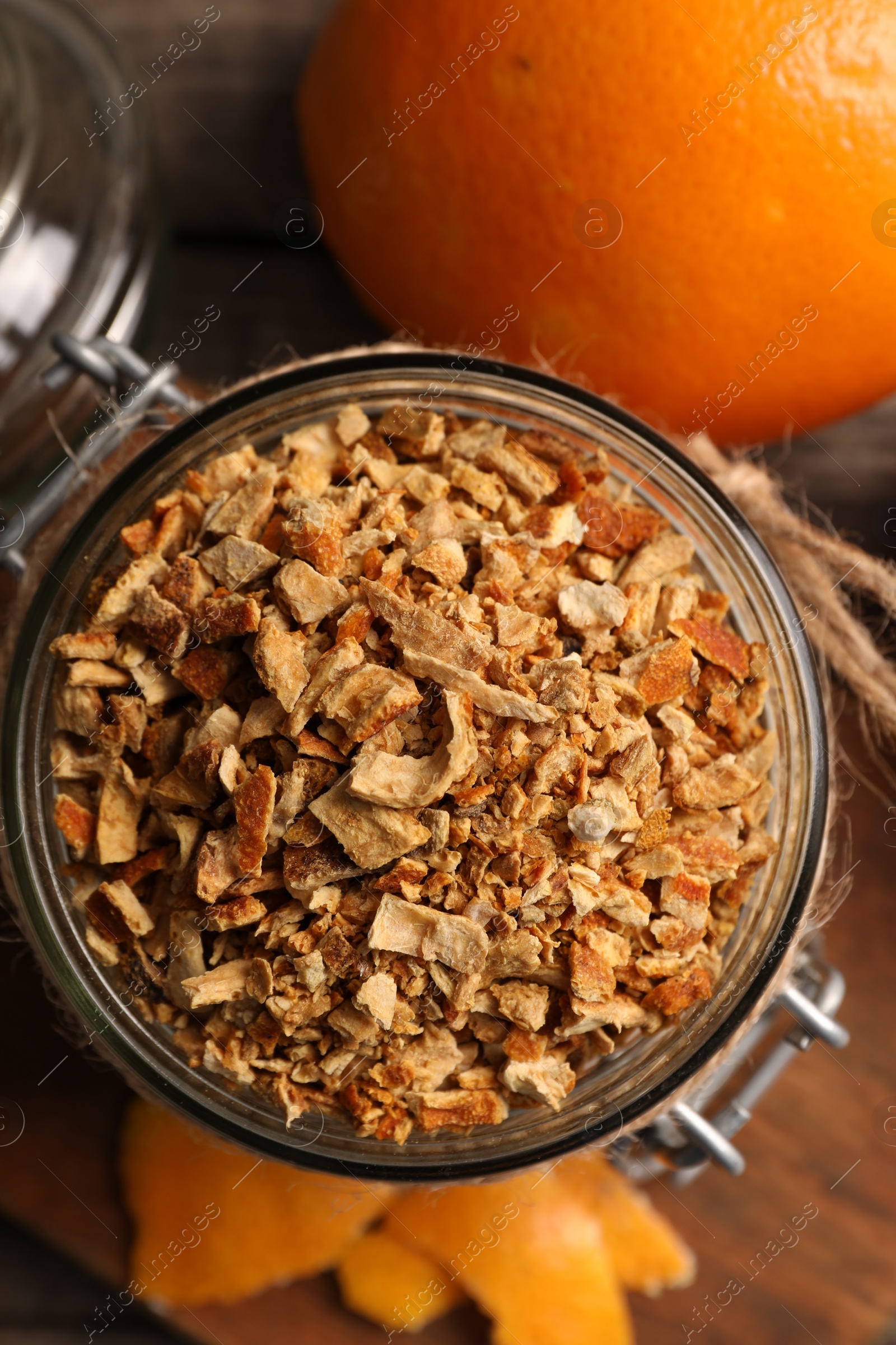 Photo of Jar of dried orange zest seasoning and fresh fruits on wooden table, flat lay