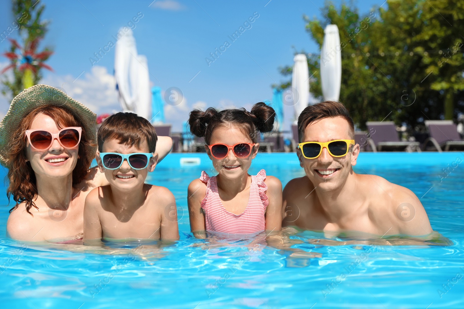 Photo of Happy family in swimming pool at resort