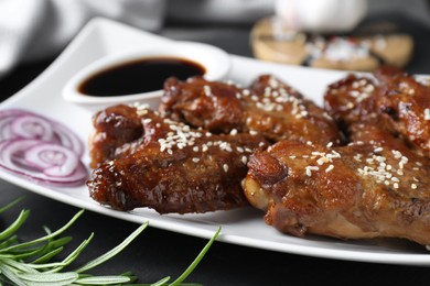 Photo of Chicken wings glazed with soy sauce served on table, closeup