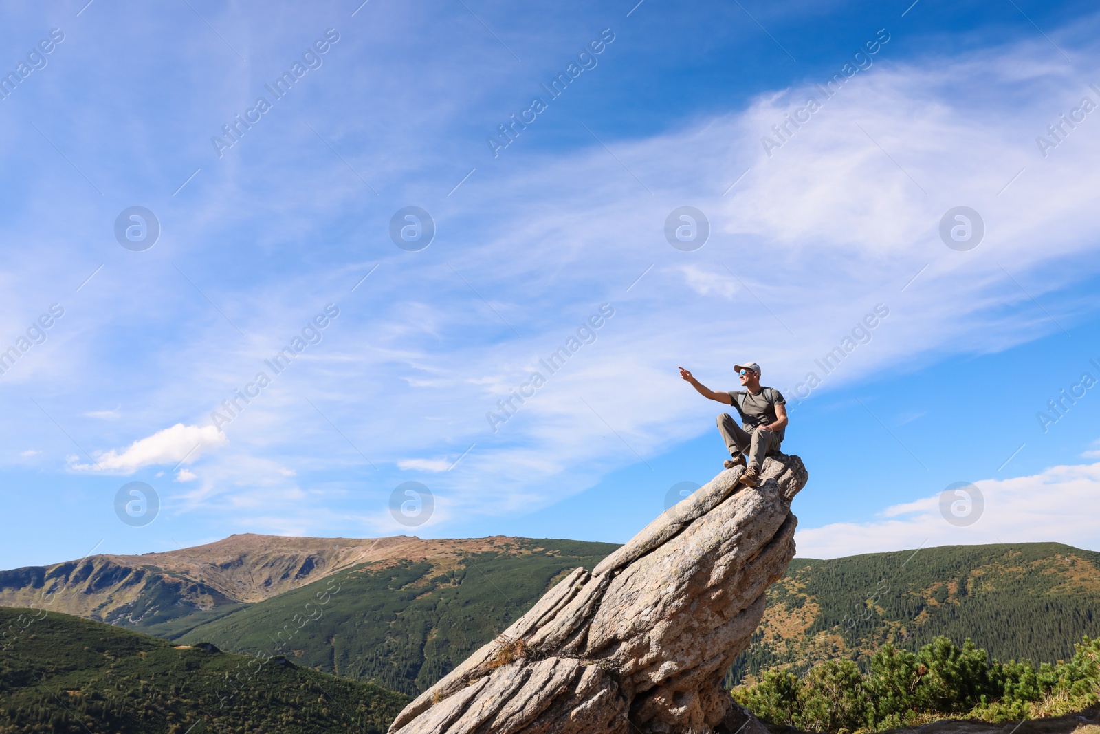 Photo of Man enjoying picturesque view on cliff in mountains. Space for text