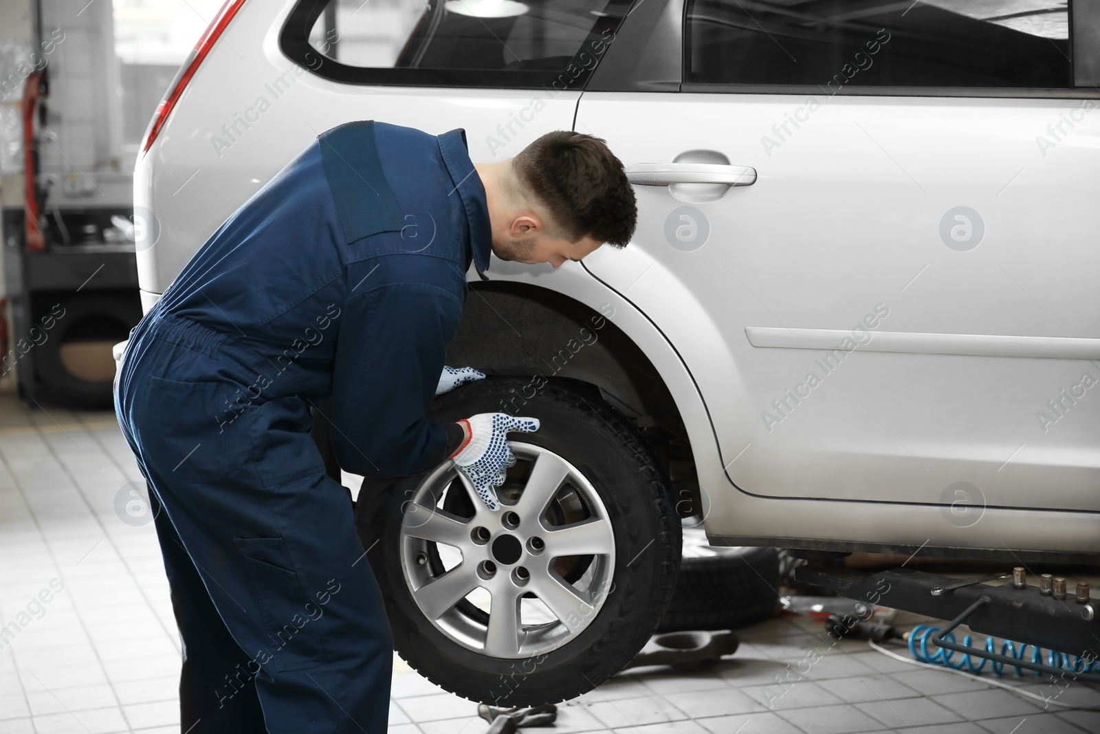 Photo of Young mechanic changing wheel at tire service