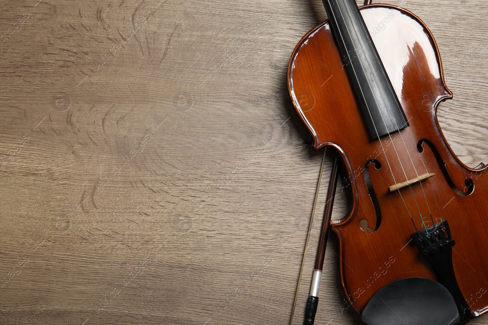 Photo of Classic violin and bow on wooden background, top view. Space for text