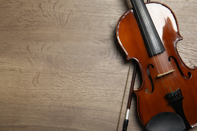 Photo of Classic violin and bow on wooden background, top view. Space for text