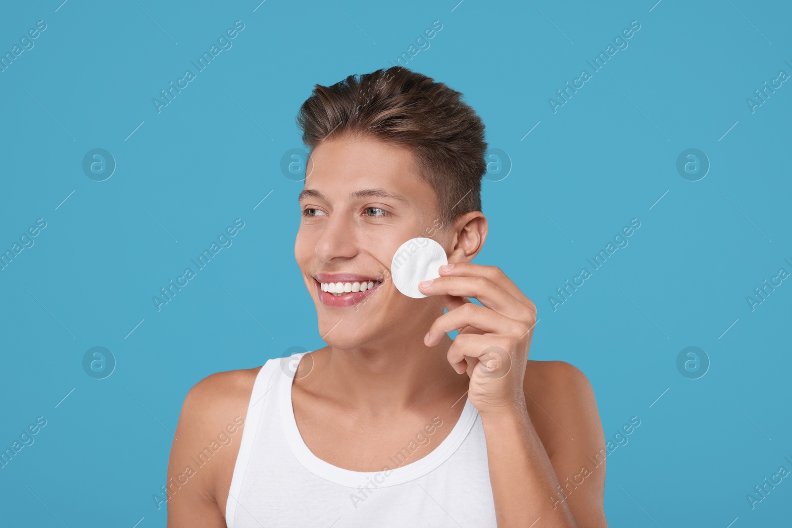 Photo of Handsome man with cotton pad on light blue background