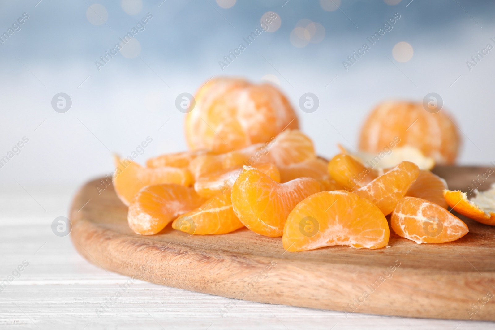 Photo of Segments of fresh juicy tangerines on white wooden table, closeup