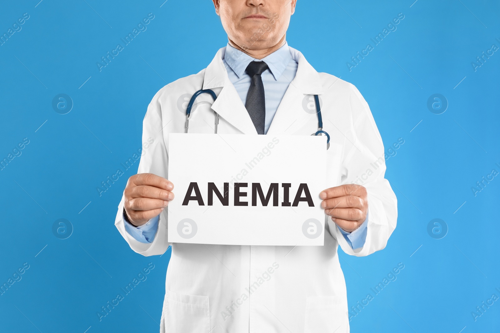 Image of Doctor holding sign with word ANEMIA on blue background, closeup